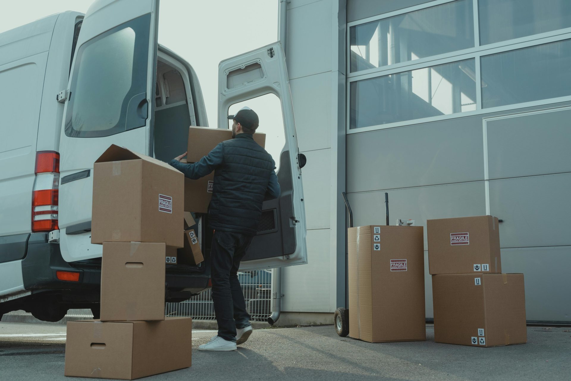 Delivery person with boxes by silver van.