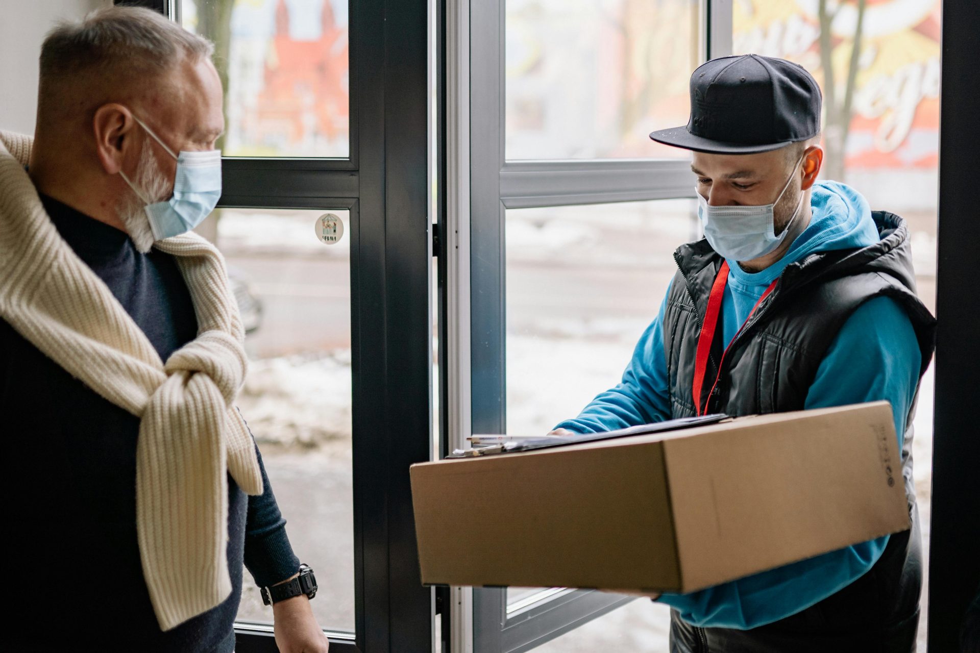 Delivery person handing package to masked man.